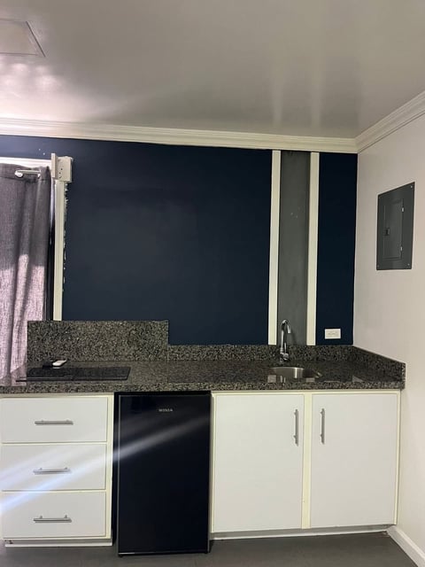 Cocina con gabinetes blancos, cubierta de granito oscuro y salpicadero negro