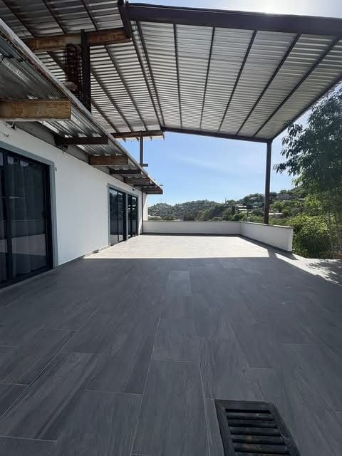 Deck exterior con pérgola metálica y piso de madera oscura