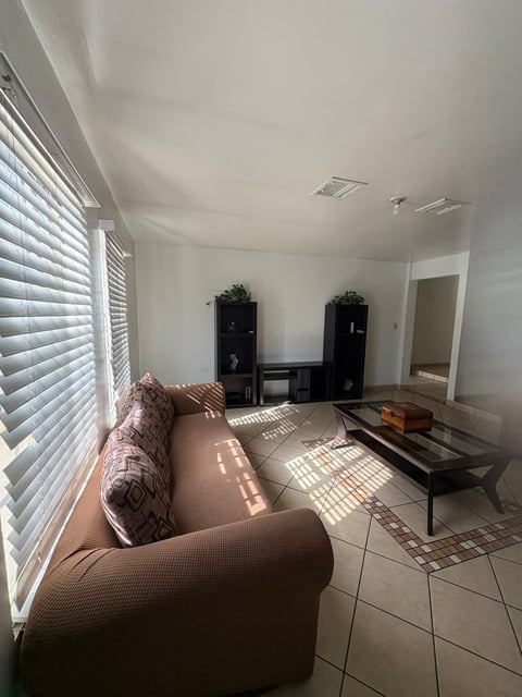 Sala luminosa con muebles beige, ventanas con luz natural y pisos de loseta