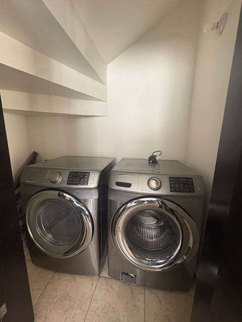 Cuarto de lavado moderno con dos lavadoras grises de carga frontal lado a lado y paredes blancas
