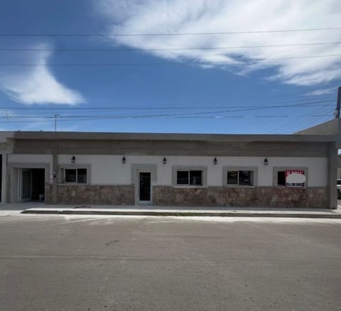 Fachada principal de edificio comercial de una planta con muros blancos, fachada de piedra y letrero de Se Renta