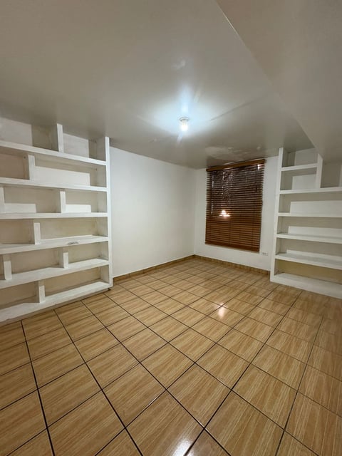 Habitación adicional con piso de madera y repisas blancas