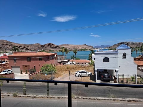 Vista panorámica de la bahía de San Carlos con casas modernas rosa y blanco, crucero en el mar y cerros rocosos