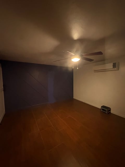 Habitación con puerta de granero oscura, ventilador de techo con luz y minisplit en pared