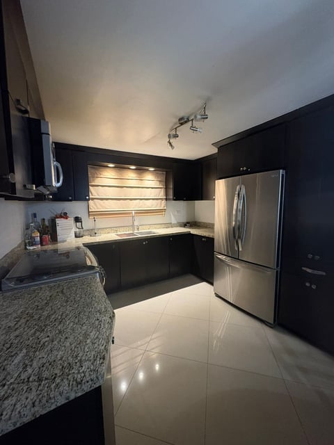 Cocina moderna con gabinetes negros, electrodomésticos de acero, cubierta de granito y tragaluz