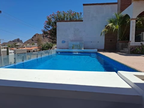 Alberca privada azul brillante en terraza con vista panorámica al cerro y pueblo