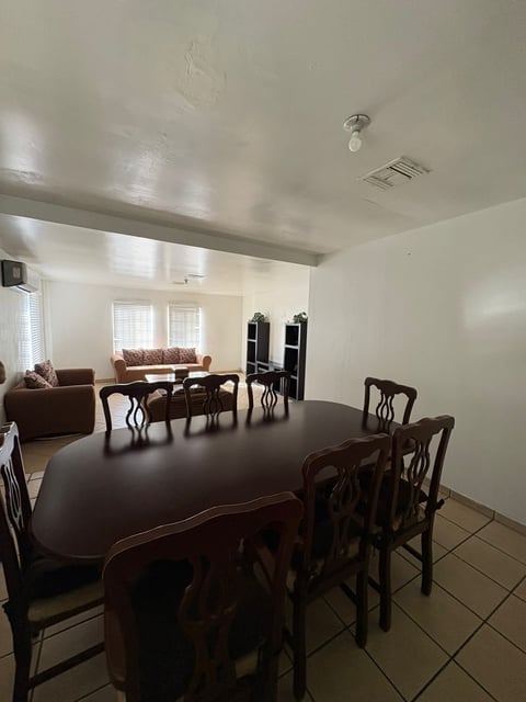 Sala-comedor con mesa de comedor de madera oscura, sofá café y centro de entretenimiento