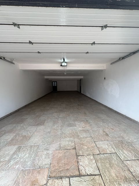 Cochera interior con muros blancos, portón y piso de concreto