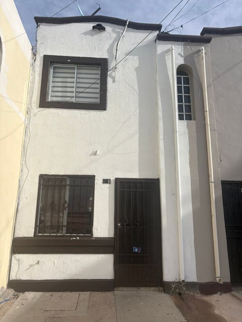 Fachada de edificio residencial de dos pisos color blanco con detalles café