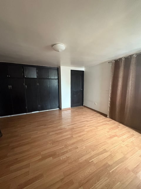 Recámara con piso de madera, clósets integrados negros y cortinas café