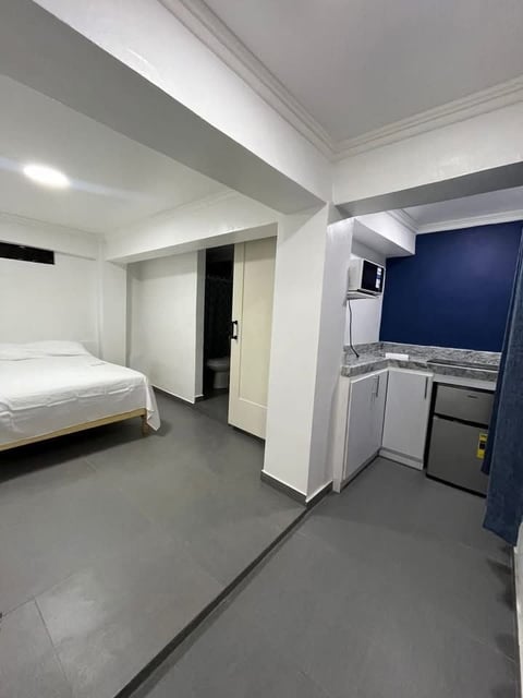 Estancia tipo estudio con cama, cocineta y pisos de concreto pulido