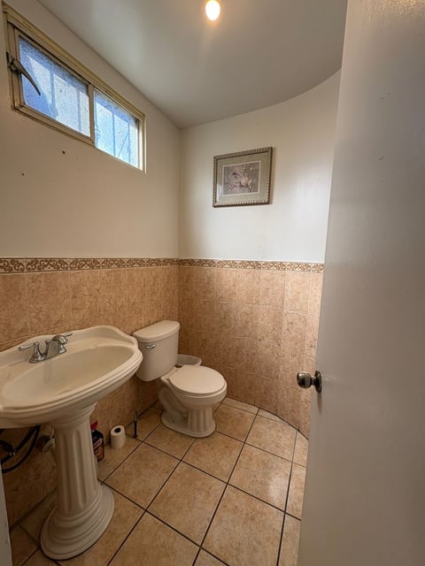 Baño con lavamanos de pedestal, inodoro y muros de loseta