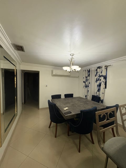 Comedor con mesa de concreto gris, sillas tapizadas en negro y lámparas colgantes