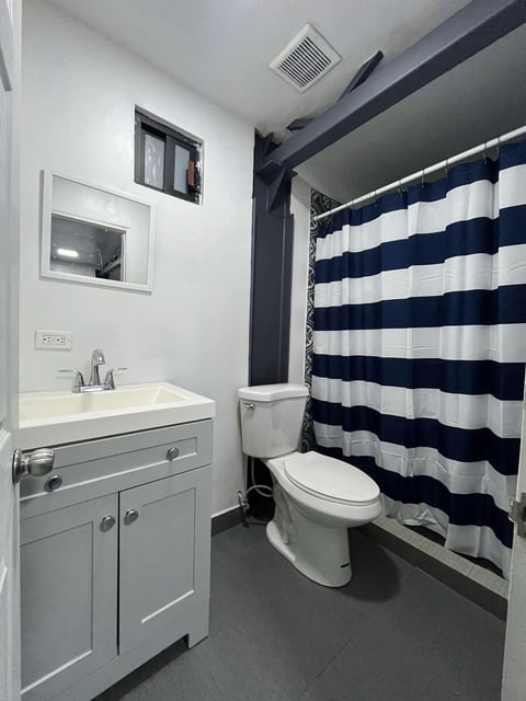 Baño moderno con lavamanos blanco, inodoro y cortina de regadera azul marino