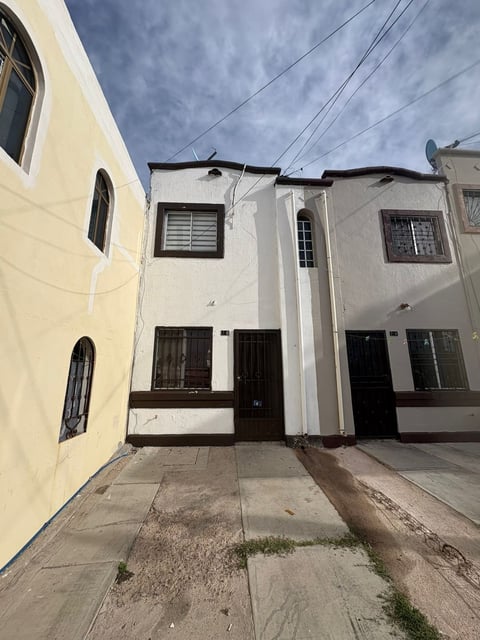 Vista del conjunto de townhouses de tres pisos con fachadas blancas y crema