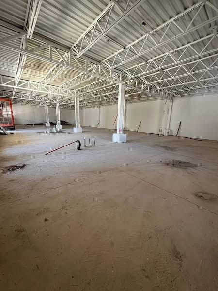 Interior amplio del local con vigas de acero blanco, techo de lámina corrugada y piso de concreto