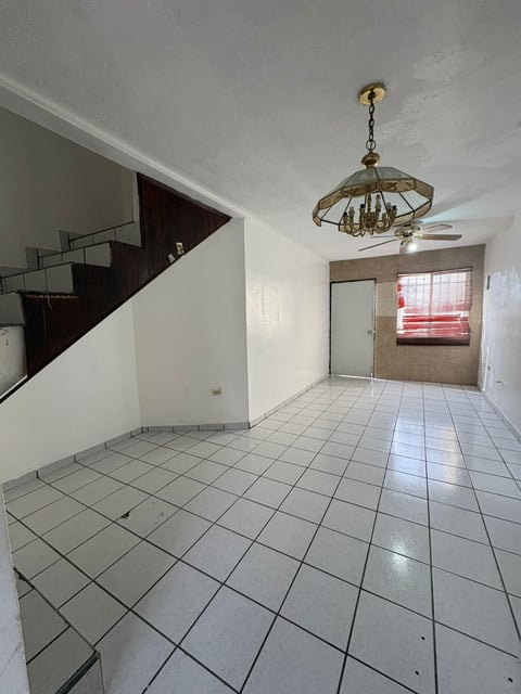 Estancia interior con piso de loseta, lámpara colgante y escalera