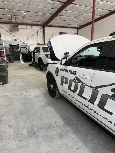 North Park Police vehicles parked in maintenance garage with open hood on white patrol car