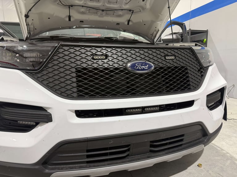 White Ford vehicle with open hood displayed in indoor service area, showing front grille and engine compartment