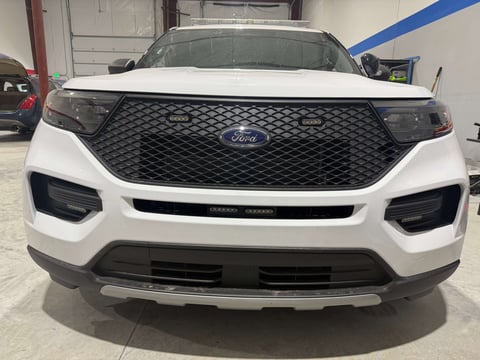 White Ford Explorer SUV front view in showroom with black grille and headlights