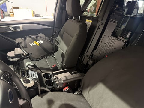 Police vehicle interior with partition and cargo area behind front passenger seat