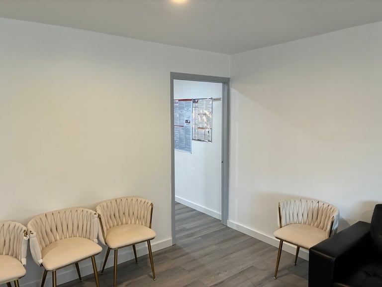 Welcoming waiting room with comfortable beige chairs, dark wood floors, and an open doorway