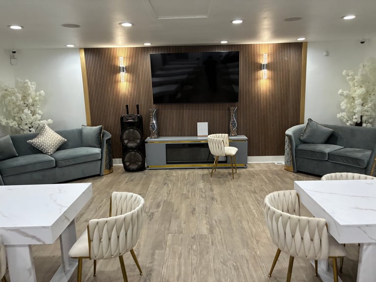 Cozy living room with gray velvet sofas, wall-mounted TV, wood accent wall, and dining area with white chairs