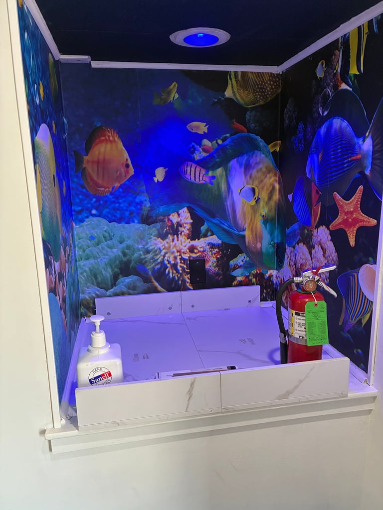 Whimsical, ocean-themed handwashing station with tropical fish murals, coral designs, and soft blue ceiling lighting — a small, joyful detail that shows how thoughtfully our spaces are designed