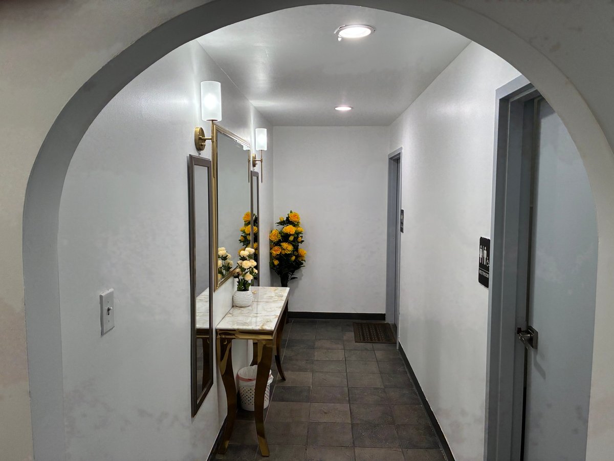 Elegant hallway with arched entrance, marble console table with yellow flowers, mirrors and warm wall sconces