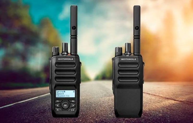 Two black Motorola two-way radios standing on a road with colorful sky background