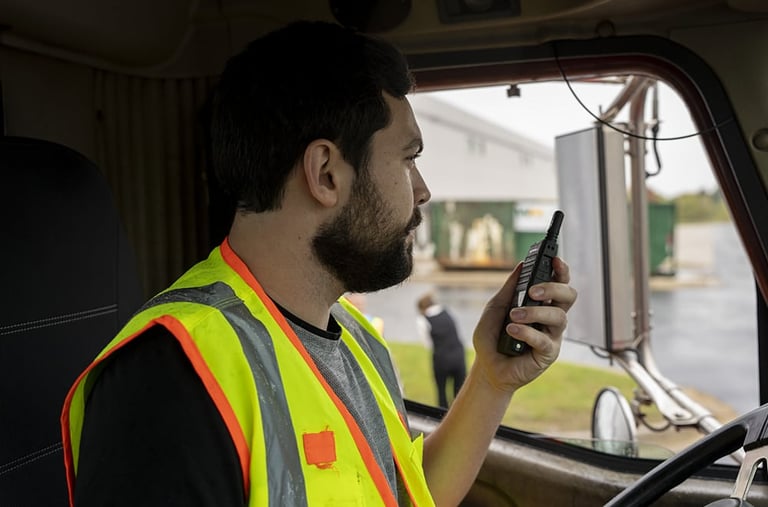Worker in yellow safety vest holding walkie-talkie inside vehicle cab