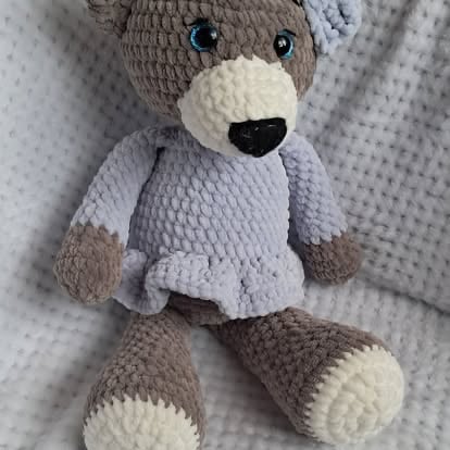 Handmade crocheted teddy bear with gray and cream coloring, black nose and eyes, wearing a light purple sweater