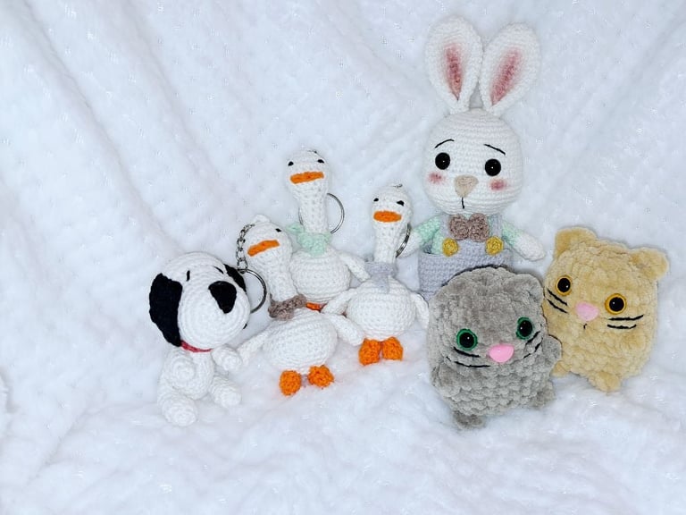 Collection of crocheted winter characters including snowmen, a bunny, and teddy bear sitting on white snow