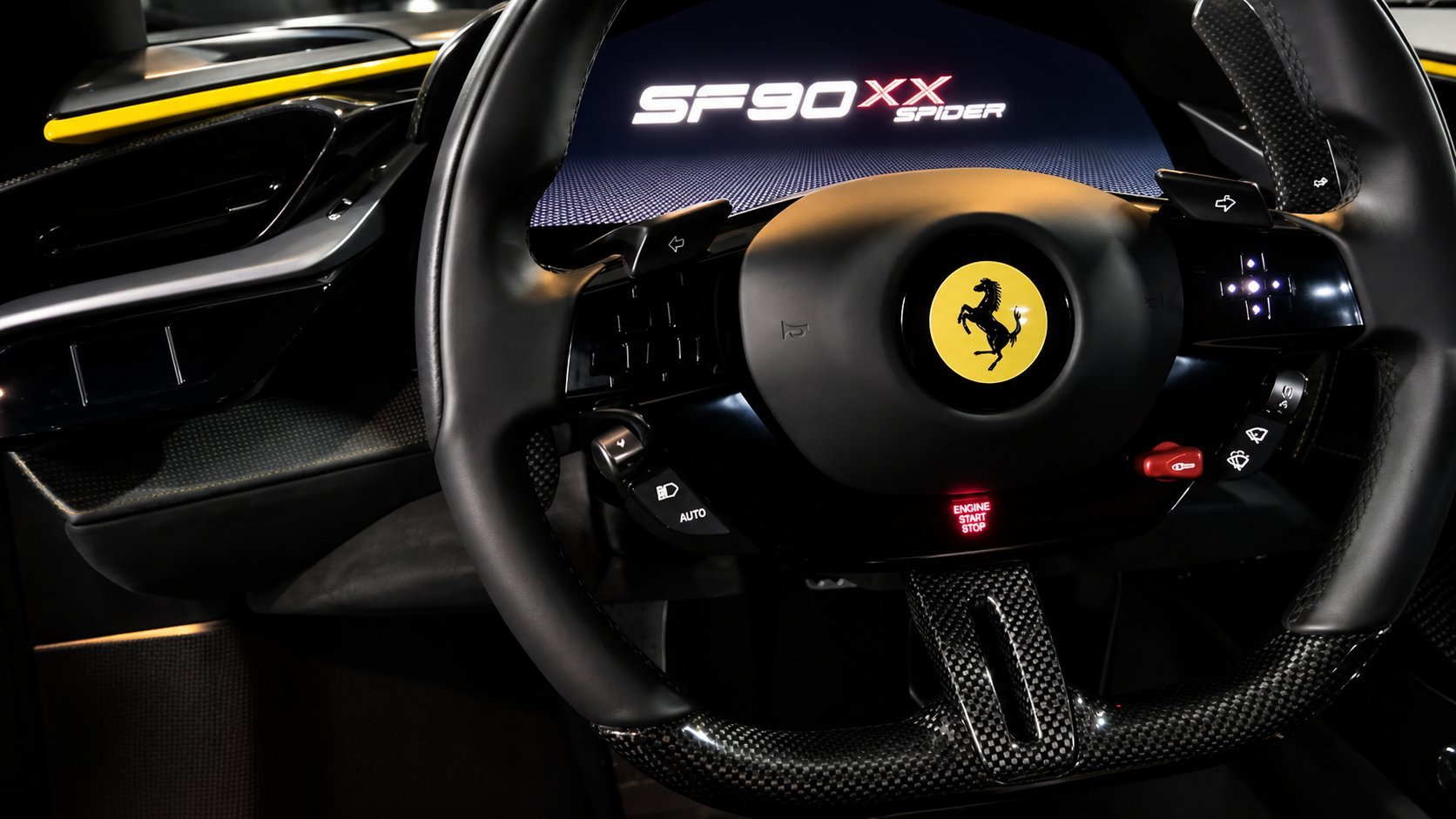 Close-up of a Ferrari SF90XX steering wheel with yellow Prancing Horse logo and black leather grip