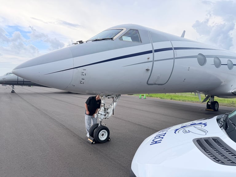 Silver business jet parked on tarmac with landing gear down and blue stripe detail on fuselage