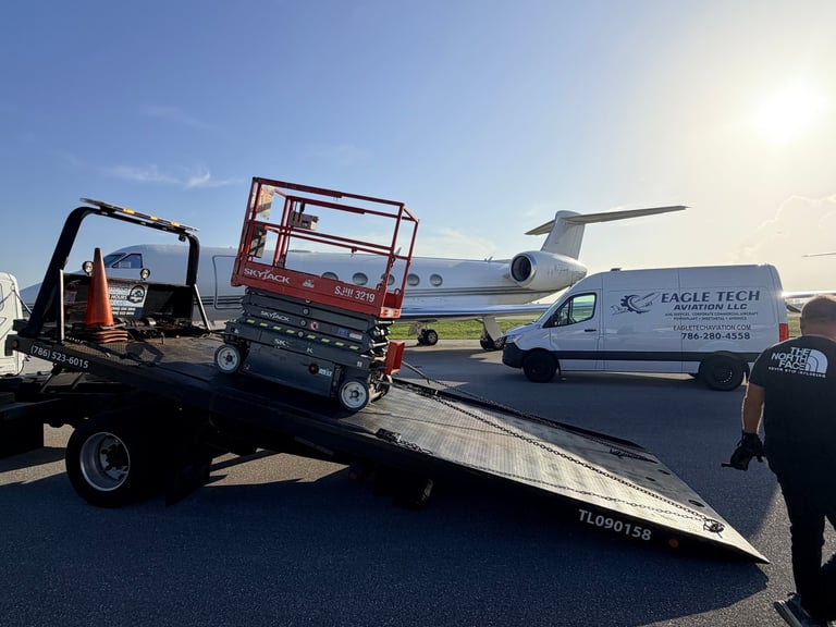 Tow truck carrying a red scissor lift on airport tarmac with airplane and van in background