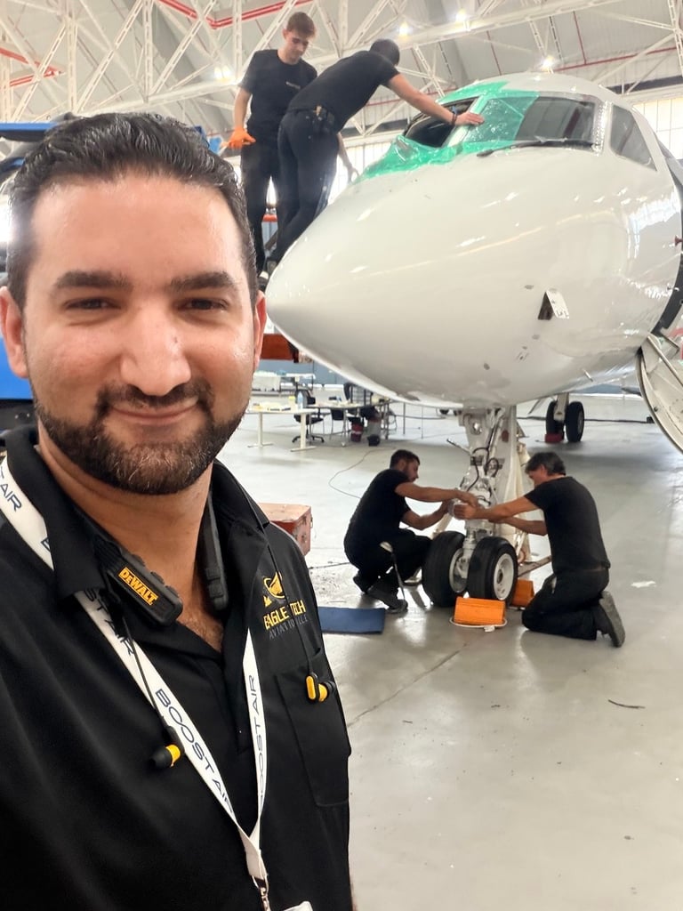 Eagle Tech Aviation technician in branded jacket with maintenance team servicing a white aircraft in a hangar