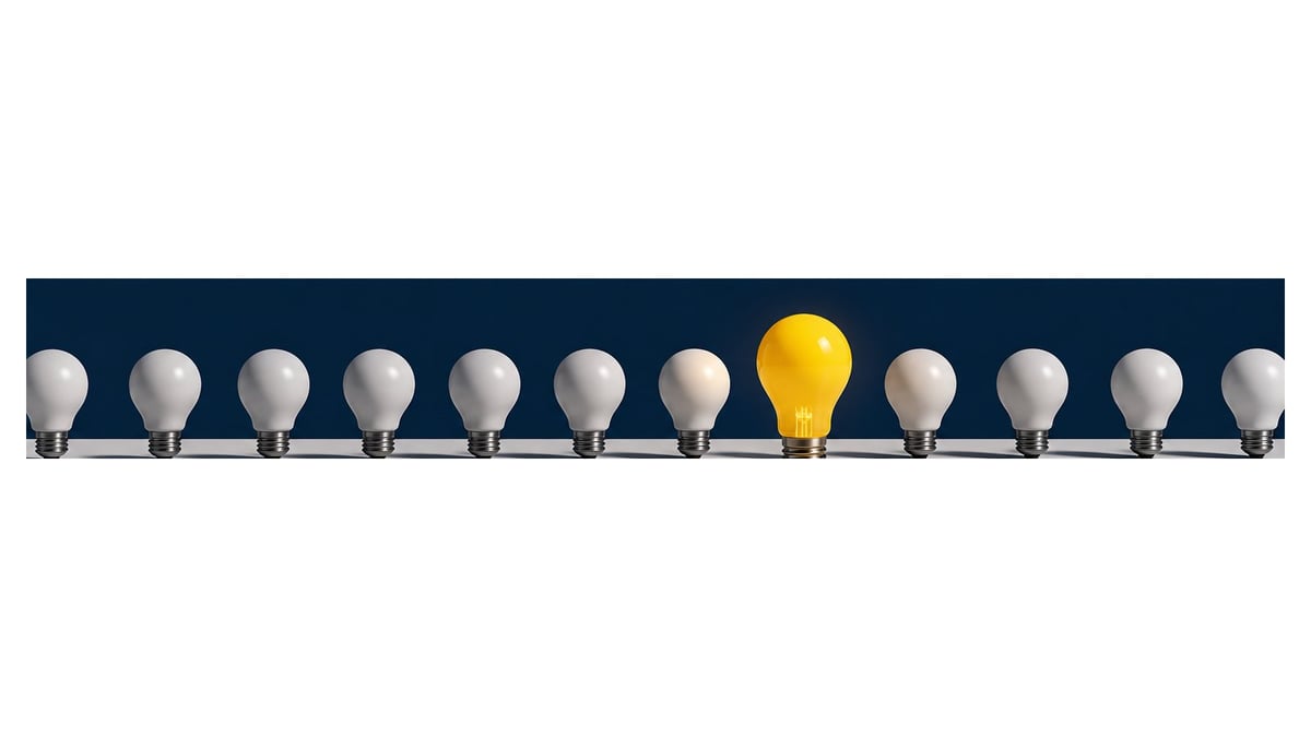 Row of light bulbs on dark background with one yellow bulb standing out among gray ones