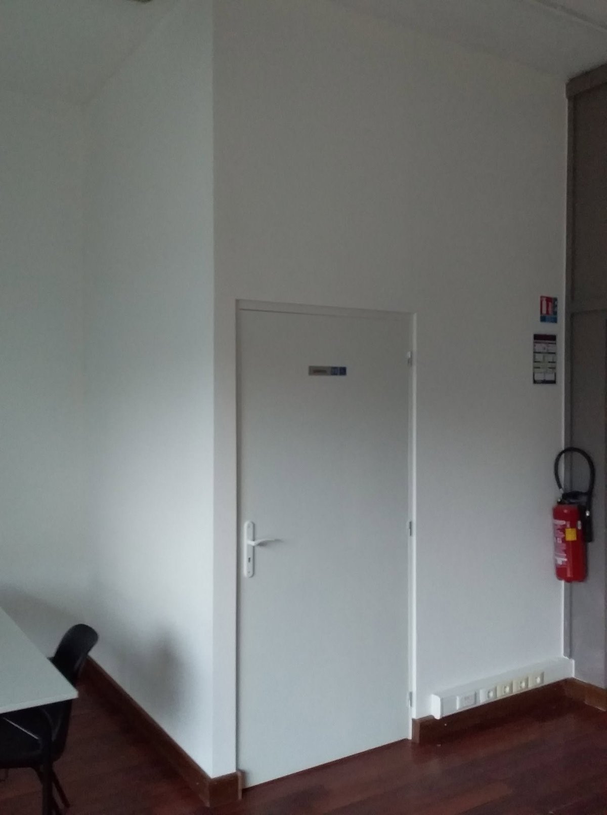 White interior door in hallway with fire extinguisher mounted on wall and baseboard heater below