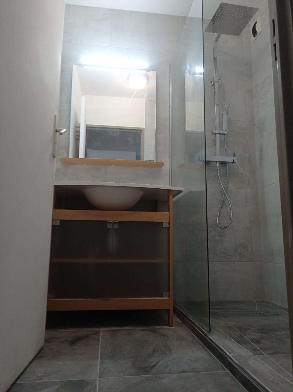 Modernes Badezimmer mit Holzwaschtisch, rundem Aufsatzwaschbecken, großem Spiegel mit LED-Beleuchtung und glasabgetrenntem Duschbereich