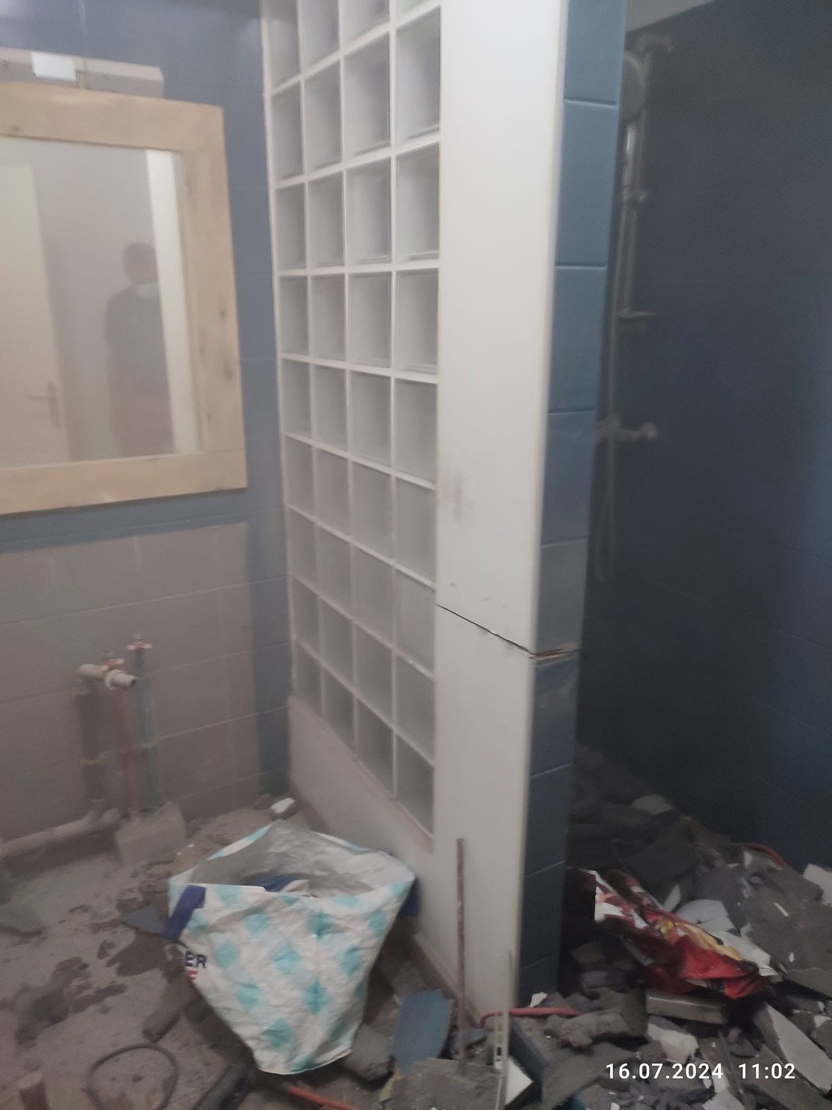 Vorher — Badezimmer während der Sanierung mit weißem Einbauschrank, freiliegender Wand und Bauschutt auf dem Boden