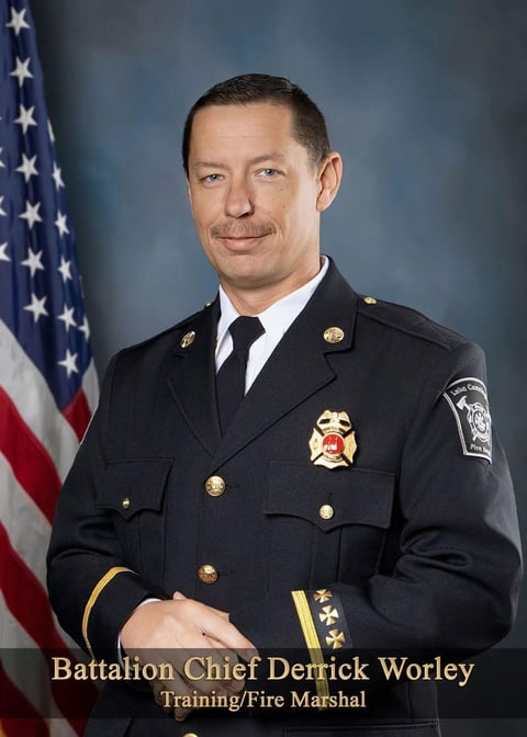 Official portrait of Battalion Chief Derrick Worley, Training and Fire Marshal, in dress uniform with American flag background