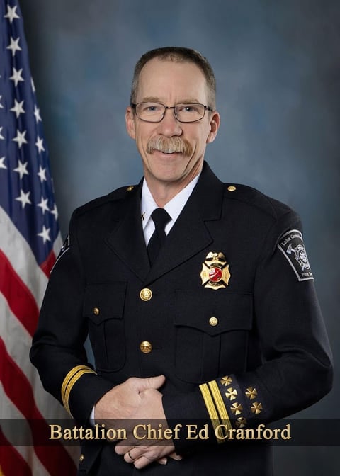 Battalion Chief Ed Cranford in formal dress uniform with American flag in background