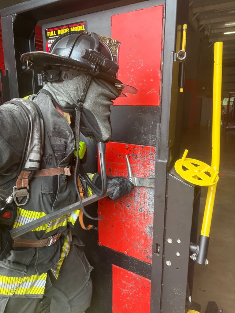 Firefighter in full protective gear training on door breaching technique with red and black equipment