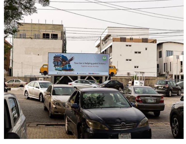 Landscape digital billboard on Bisola Durosinmi Etti Drive, Lekki Phase I — facing a busy parking lot with multiple parked cars and residential buildings behind