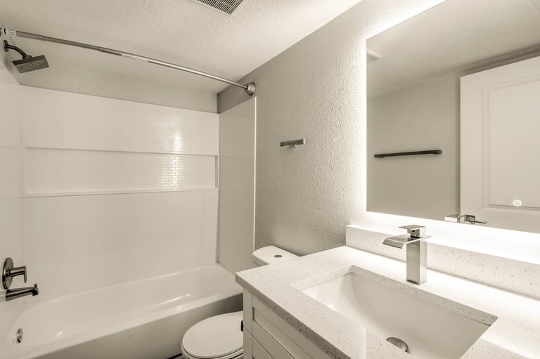 Modern bathroom with white vanity, sink, mirror, and tiled shower enclosure with white subway tile walls