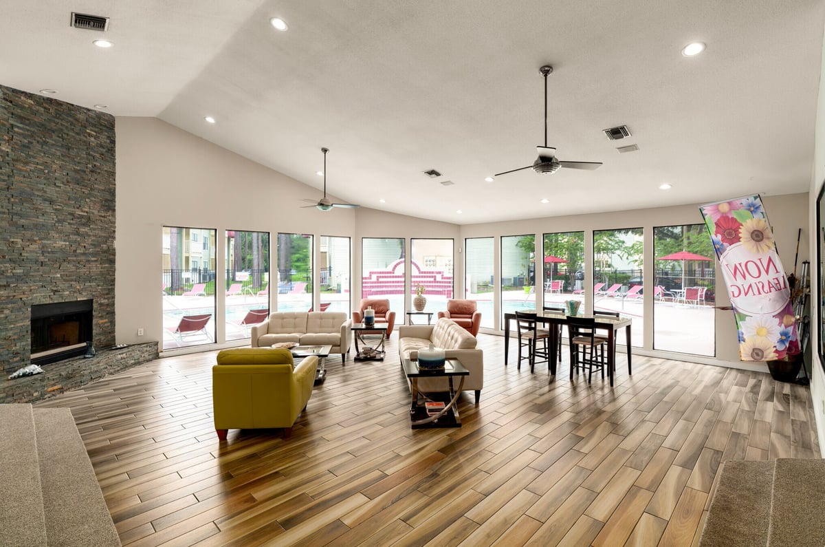 Modern open-concept living room with wood floors, olive green furniture, fireplace, and glass doors leading to patio