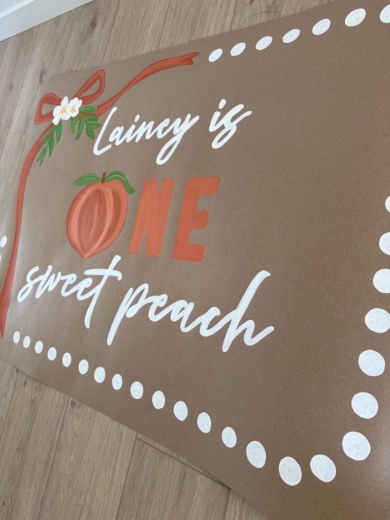 Decorative wall sign with text Liking is ONE sweet peach featuring an illustrated peach, flowers, and white polka dot border on tan background