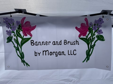 Business banner for Banner and Brush by Morgan LLC with watercolor flowers and text hung on black clips