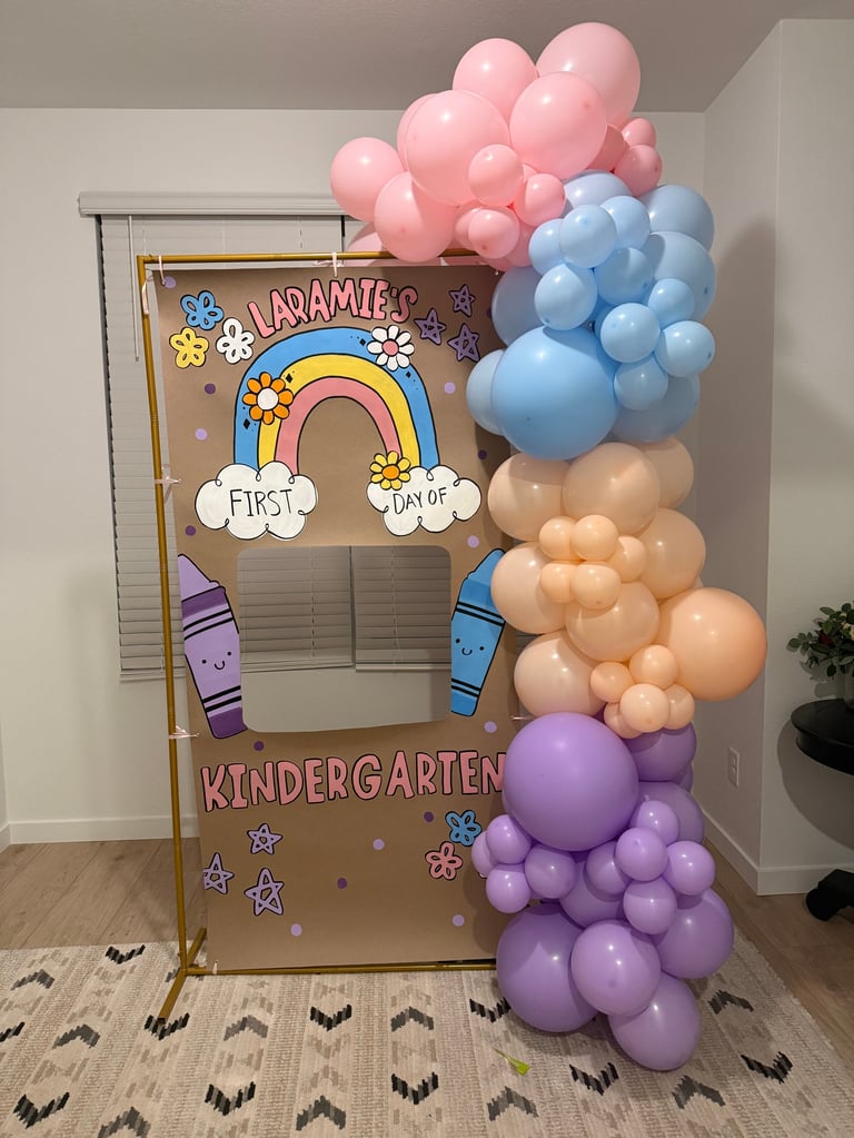 First day of kindergarten cardboard cutout decorated with colorful balloons in pink, blue, tan, and purple